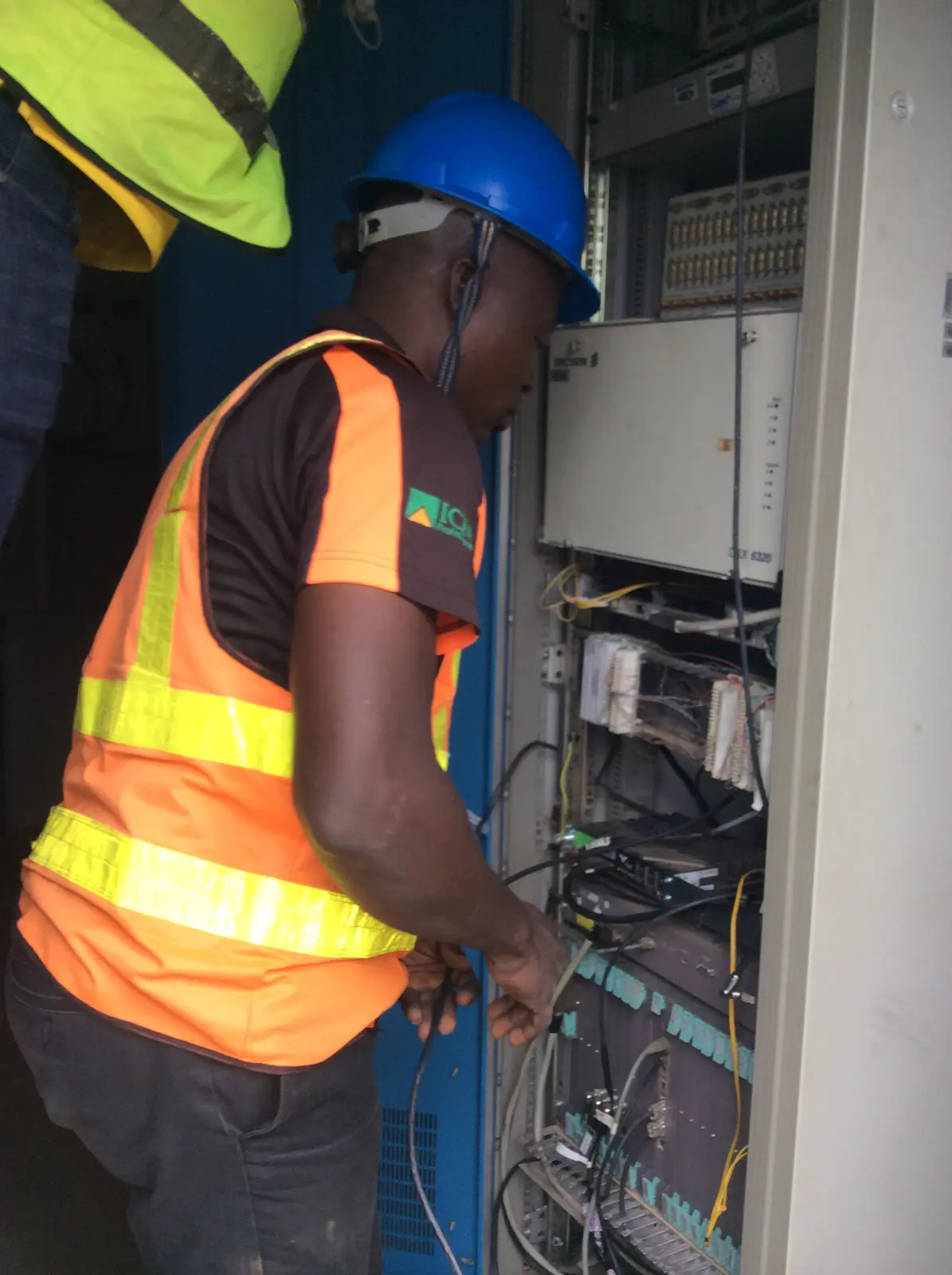 Field technician maintaining equipment inside a site cabinet