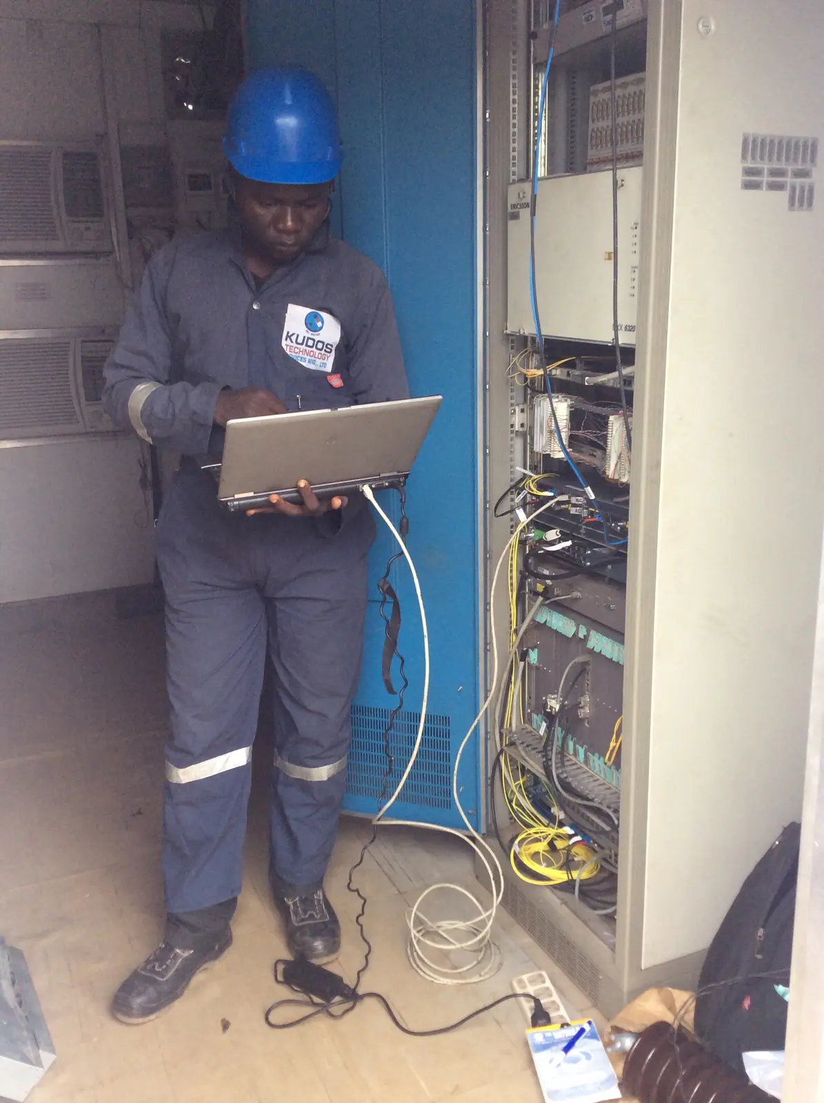 Kudos engineer commissioning telecommunications equipment with a laptop