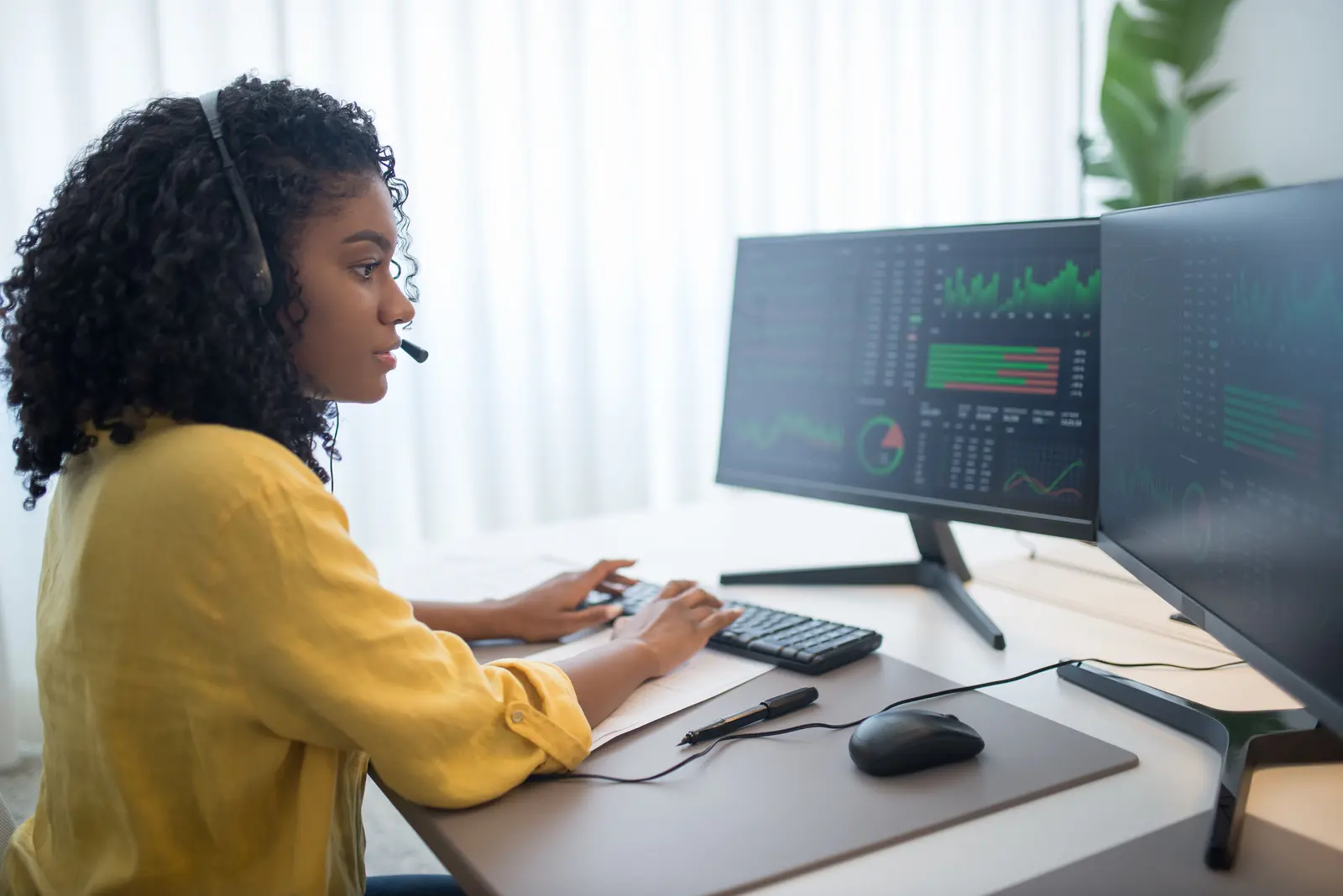 Black technology professional analysing information across dual monitoring screens